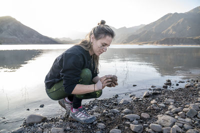 Woman putting mud on hands and face while enjoying outdoors in nature.