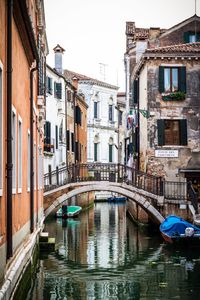 Arch bridge over canal amidst buildings in city