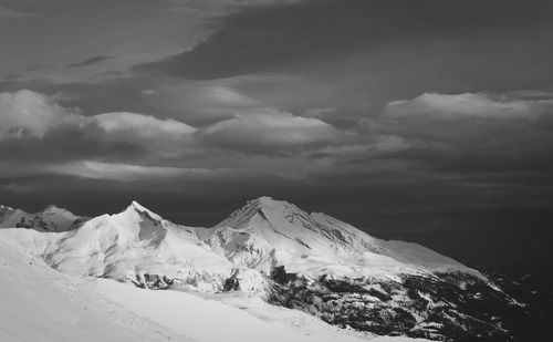 Snow covered mountains against cloudy sky