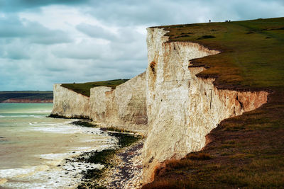 Scenic view of beach against cloudy sky