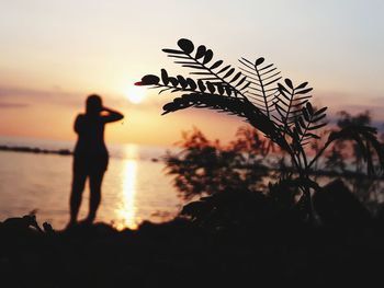 Silhouette person standing on beach against sky during sunset