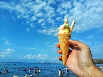 People holding ice cream on beach against sky