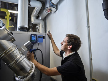 Chimney sweeper examining exhaust gases in boiler room
