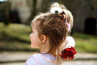 Innocent girl holding red petals with hand behind head