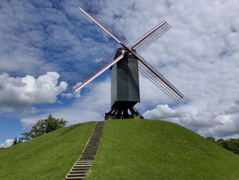 Low angle view of traditional windmill on field against sky