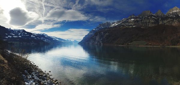 Scenic view of lake by mountains against sky