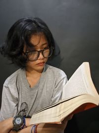 A girl reading a novel with eye glasses on