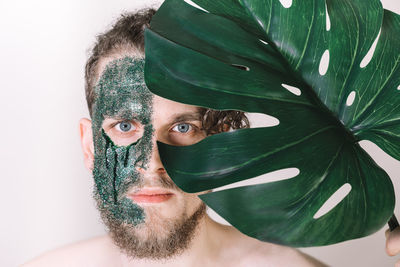 Close-up portrait of young man and leaf against white ba kground