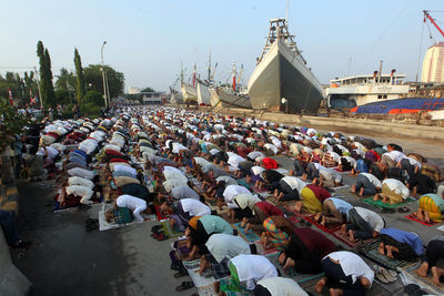 Crowd praying at commercial dock against sky