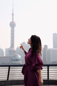 Side view of woman standing on tower against buildings in city