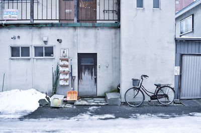 Bicycle on street against building during winter