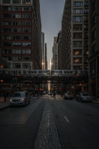 Vehicles on road in city against sky