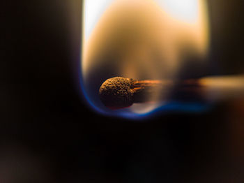 Close-up of burning candle against black background