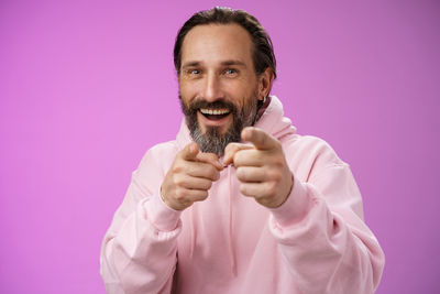 Portrait of smiling man holding pink face against gray background