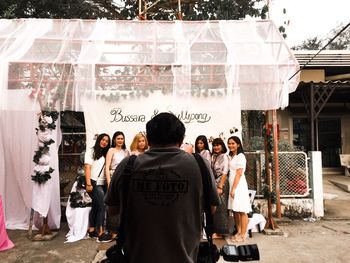 Rear view of people standing against graffiti wall