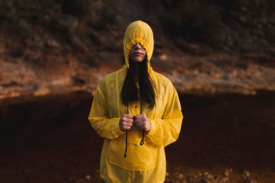 Young lady in yellow raincoat strolling in nature