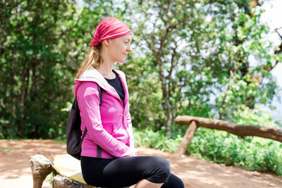 Woman looking away while sitting on tree