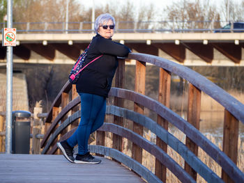 Portrait of woman standing on footbridge 