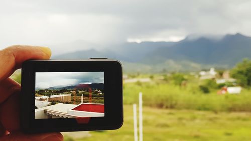 Man photographing through smart phone against sky