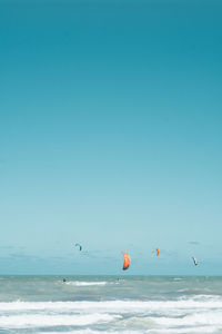 Scenic view of sea against clear blue sky and kite surf 