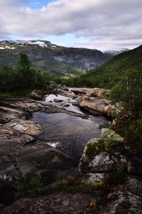Stream flowing through rocks against mountains