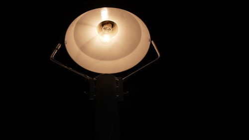 Low angle view of illuminated light bulb against black background