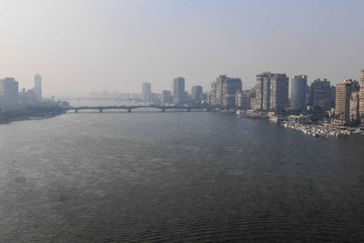 Sea by buildings in city against sky