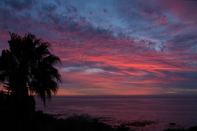 Scenic view of sea against dramatic sky during sunset
