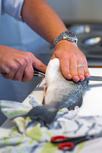 Cropped hand of man chopping fish on kitchen counter