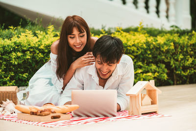 Smiling young woman sitting on table against plants