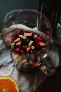 Close-up of chopped fruits in wine on glass jar at table