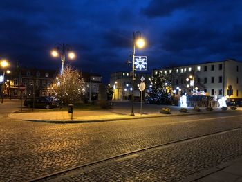 Illuminated city street against sky at night