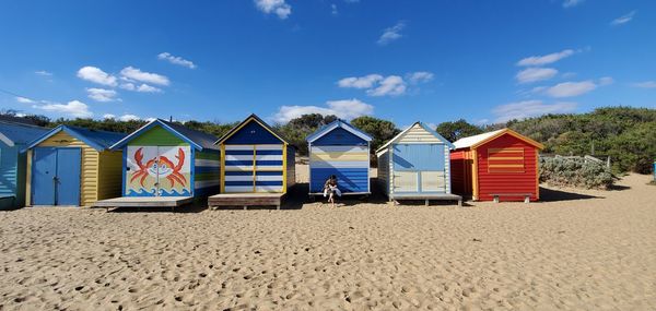 Beach huts by sea against blue sky