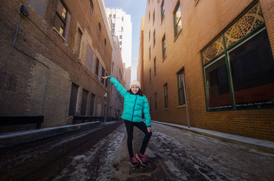 Full length of girl standing on street amidst buildings in city during winter