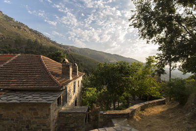 House by trees and buildings against sky