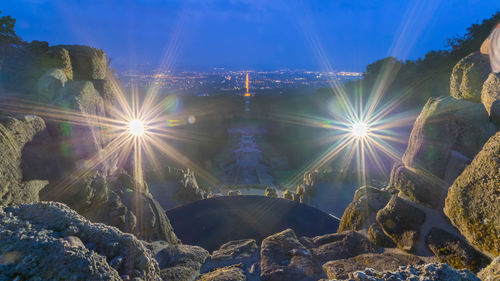 Low angle view of illuminated rocks against sky on sunny day