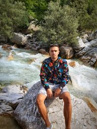 Portrait of young man standing by rock