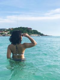 Rear view of woman in sea against sky