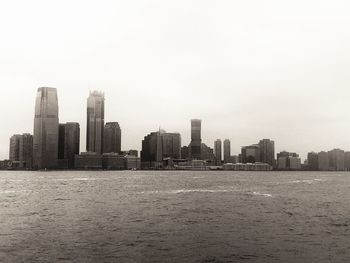 Sea by buildings against clear sky