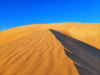 Sand dunes in desert against clear blue sky