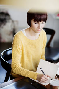 Businesswoman writing notes in book at desk