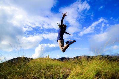 Low angle view of person paragliding on field against sky