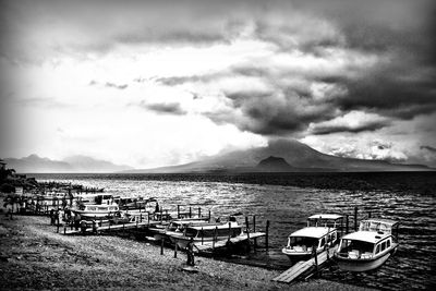 Boats in sea against cloudy sky