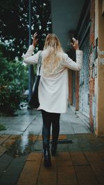 Rear view of woman walking on footpath during rainy season