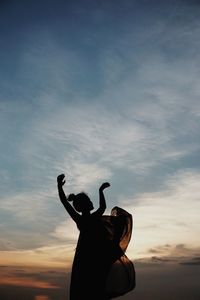 Low angle view of silhouette woman standing against sky during sunset