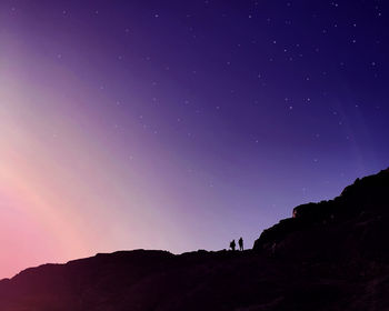 Low angle view of silhouette mountain against sky at night