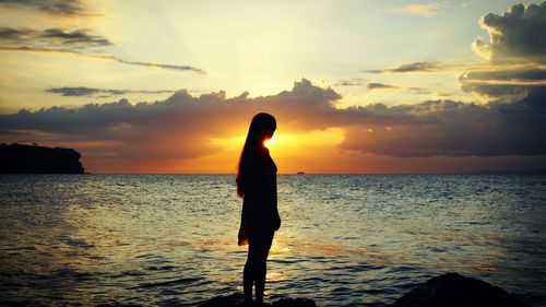 Silhouette man standing on beach against sky during sunset