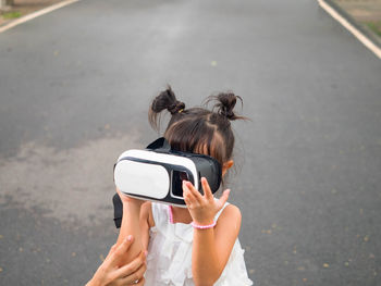 Cute girl wearing vr while standing on road