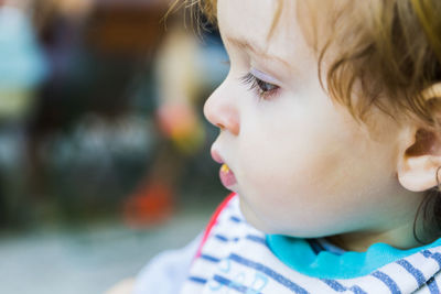 Close-up portrait of cute boy looking away outdoors