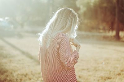 Rear view of woman standing on field during sunny day